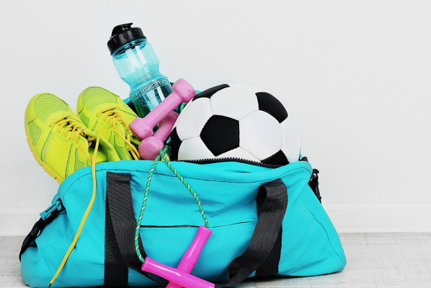 Sporttasche mit Hanteln, einem Fußball, Turnschuhen und einer Wasserflasche