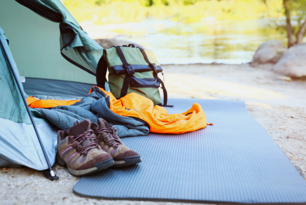 Ein Zelt mit verschiedenem Campingzubehör am Ufer eines Gewässers