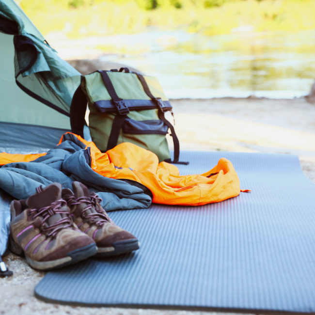 Ein Zelt mit verschiedenem Campingzubehör am Ufer eines Gewässers